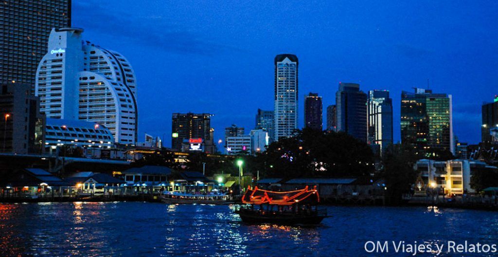 Barco iluminado navegando por el río Chao Phraya con el skyline de Bangkok al fondo, una experiencia ideal para disfrutar la ciudad de noche y descubrir que ver en Bangkok en 2 dias.