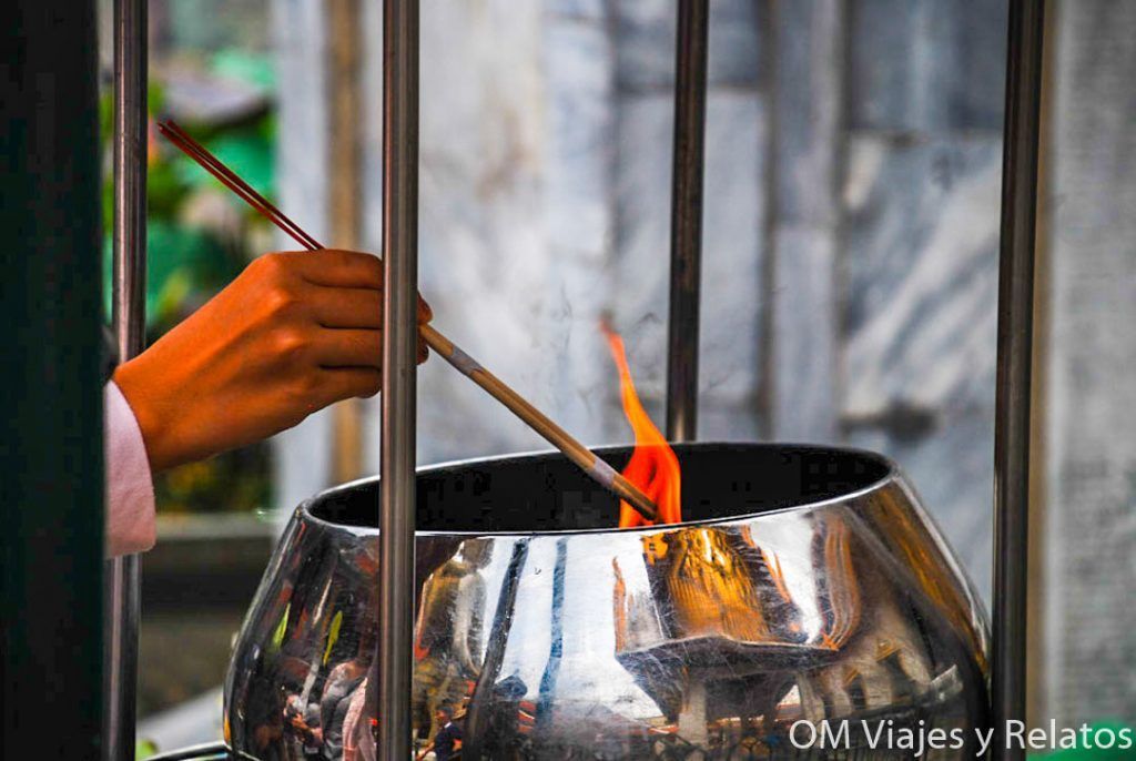 Mano encendiendo varillas de incienso en un templo de Bangkok, una escena espiritual y tradicional para incluir en una guía sobre que ver en Bangkok en 2 días.