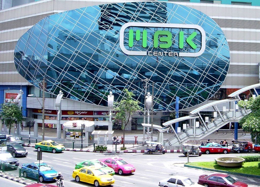 Fachada del centro comercial MBK Center con taxis de colores y tráfico urbano, una parada popular para ir de compras durante una ruta sobre que ver en Bangkok en 2 dias.