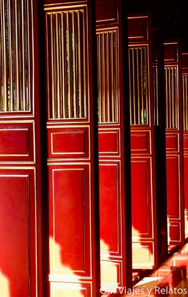 Puertas rojas tradicionales en la Ciudadela Imperial de Hue con luz natural y estética palaciega.