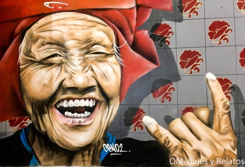 Mural de arte urbano en Chinatown con una mujer sonriente, una zona colorida y cultural que ver en Singapur en 2 dias.