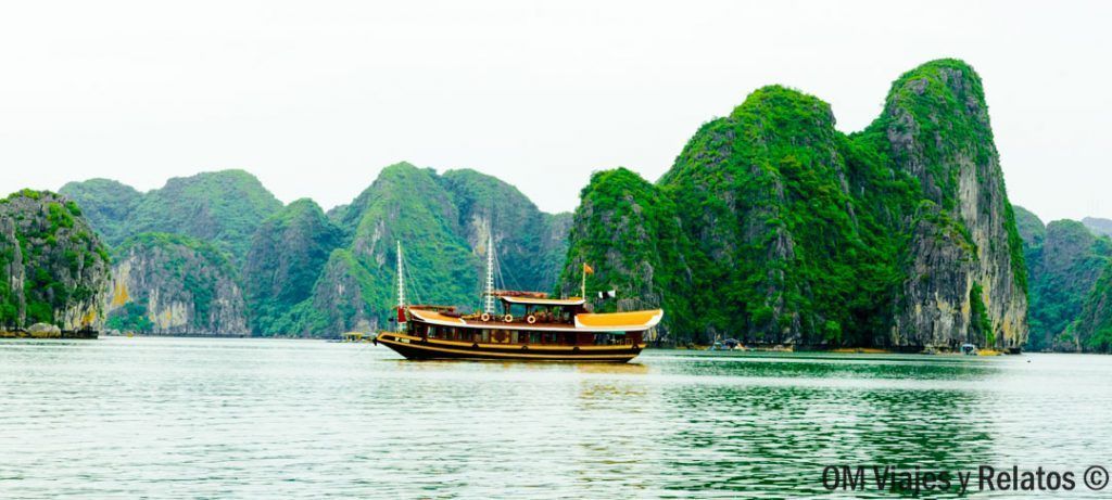 Crucero tipo junco navegando entre islotes verdes, imagen perfecta para contar como visitar la Bahia de Halong.