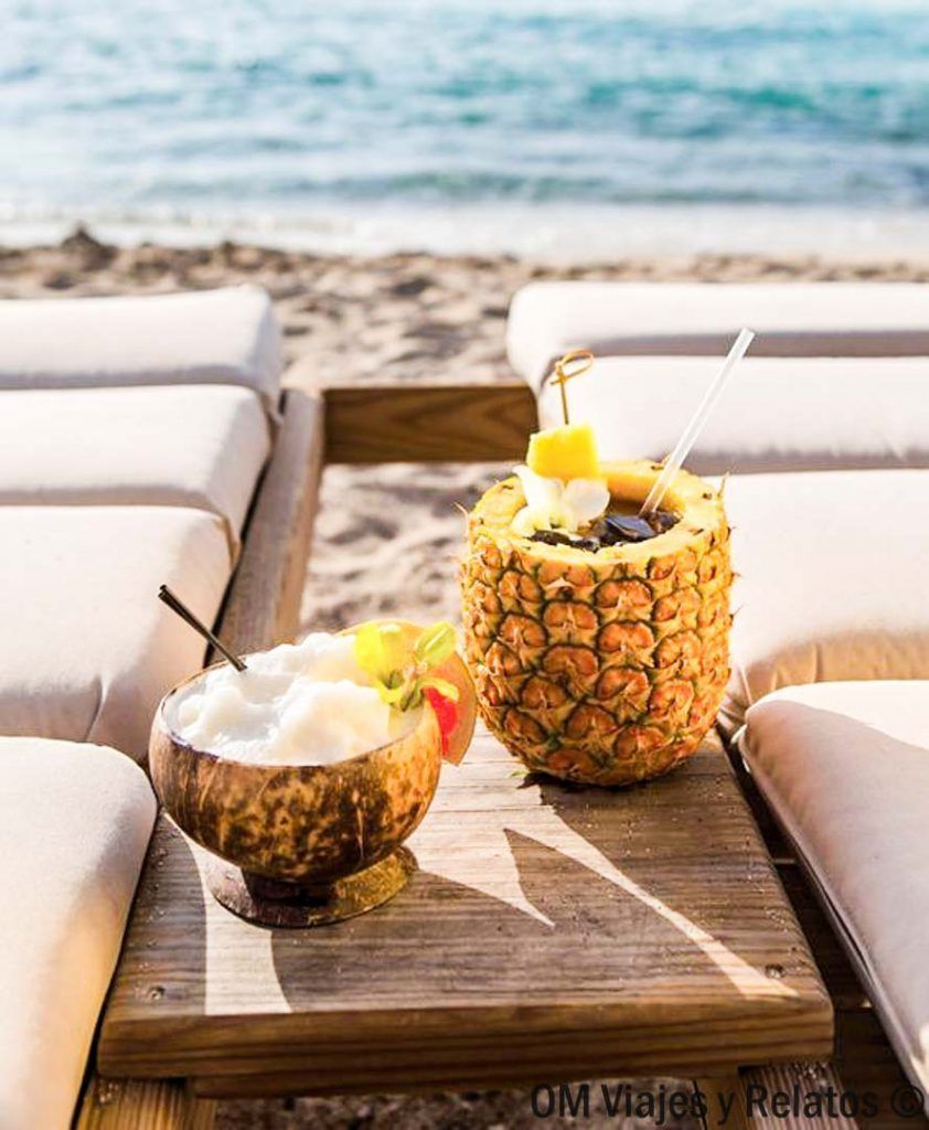 Cócteles tropicales servidos en coco y piña frente al mar, una experiencia relajante para disfrutar en las mejores playas de Hoi An.