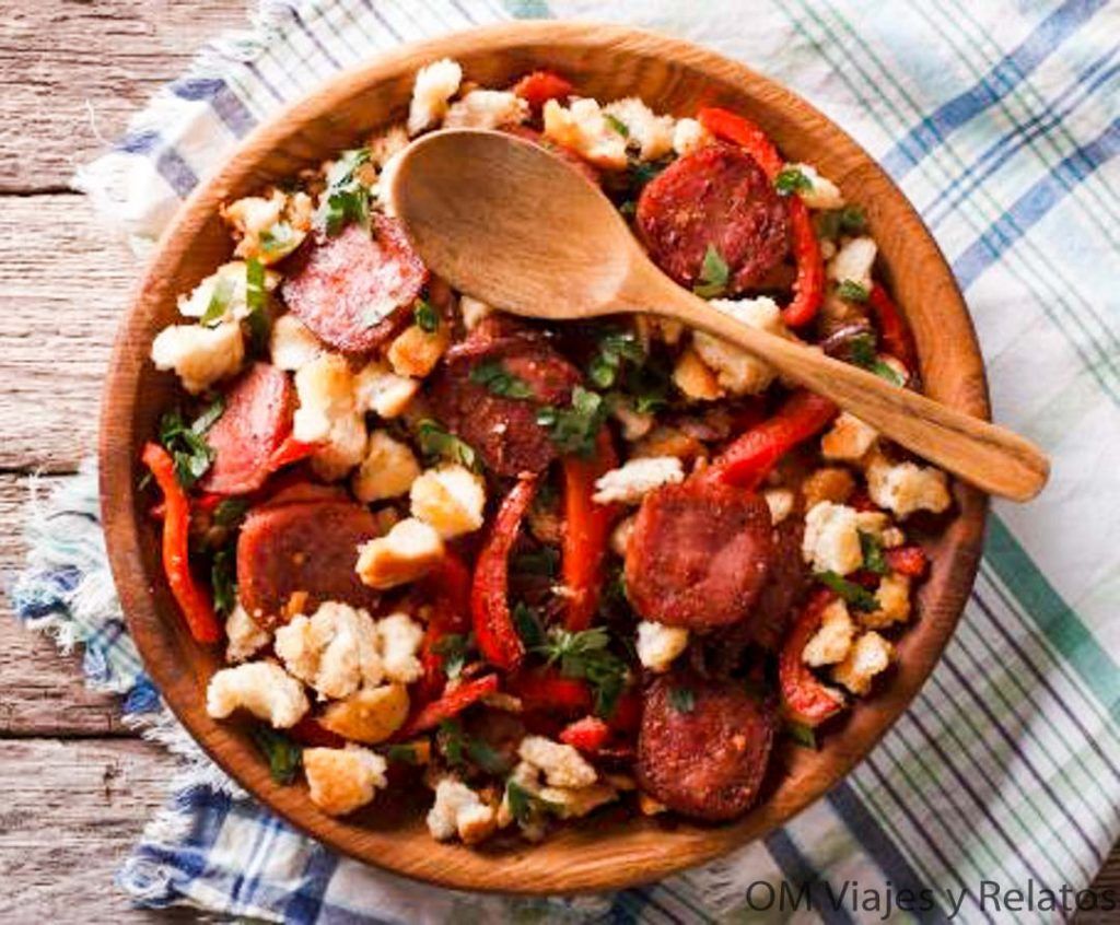 Migas extremeñas con chorizo y pimiento en cuenco de madera, plato típico para probar en pueblos más bonitos de Cáceres.