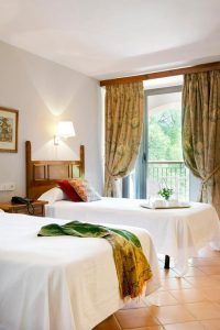 Habitación luminosa del hotel Monasterio de Piedra con dos camas individuales y balcón, una opción de alojamiento para completar tu visita a qué ver en el Monasterio de Piedra.