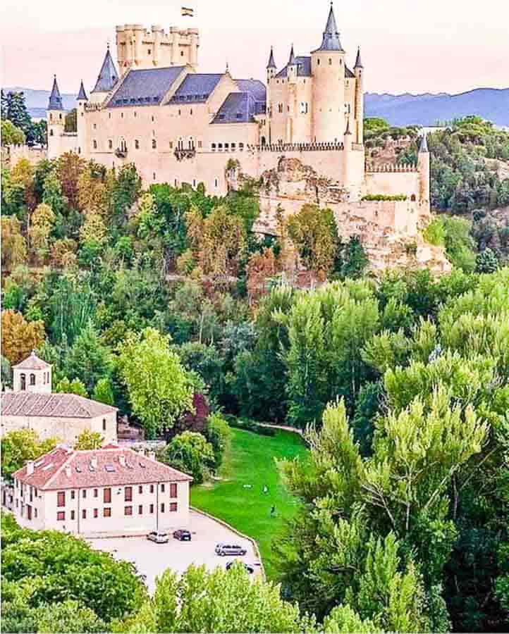 Vista del Alcázar de Segovia entre jardines y árboles, uno de los sitios para visitar cerca de Madrid.