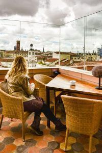 Servidora disfrutando de una terraza con vistas a los tejados de la Puerta del Sol, uno de los sitios bonitos que visitar en Madrid.