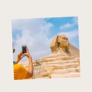 JC utilizando su móvil frente a la Esfinge de Giza, mostrando cómo el acceso a Internet en Egipto permite compartir instantáneamente momentos únicos desde lugares históricos.