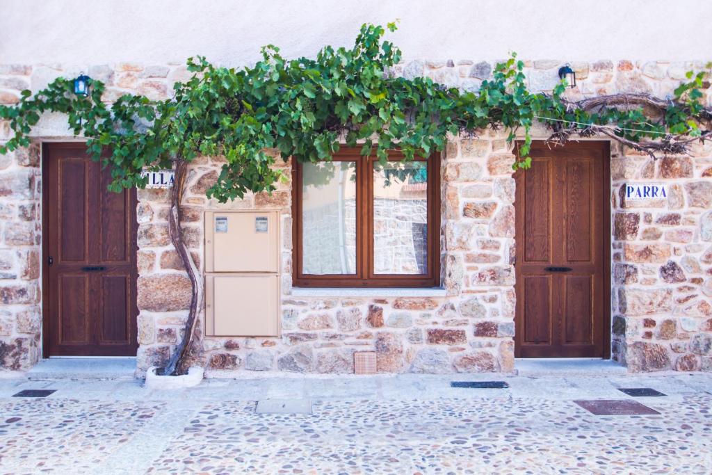 Fachada de casa de piedra con parra y puertas de madera, rincón con encanto que ver en Buitrago del Lozoya en un día.