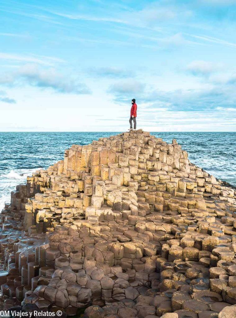 Foto de JC contemplando el mar desde las columnas basálticas de la Calzada del Gigante, una parada imprescindible en una ruta por Irlanda en coche.