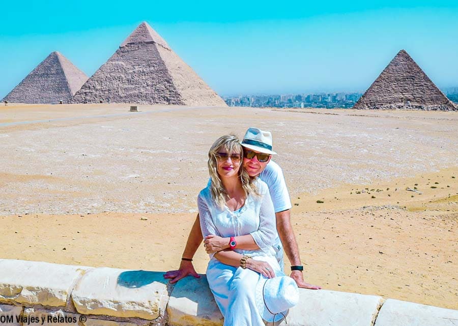 Foto de pareja OM Viajes y Relatos posando con las pirámides de Guiza al fondo, un plan imprescindible antes o después de contratar un crucero por el Nilo.