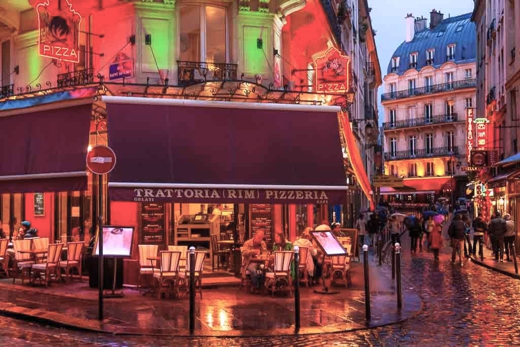 Calle con restaurantes iluminados en el Barrio Latino de París, una de las cosas romanticas que hacer en Paris.