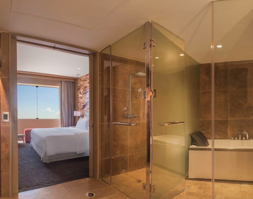 Baño moderno con ducha de cristal y vista a la habitación en el Hotel DoubleTree by Hilton, una opción cómoda que ver en Iquitos.