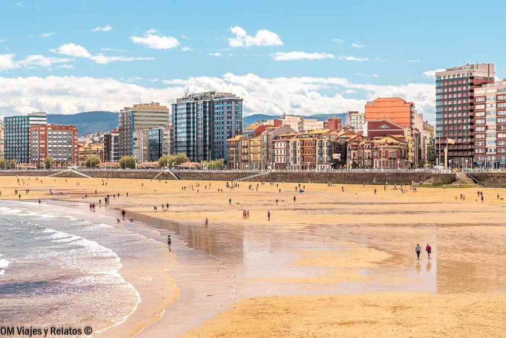 Playa urbana de Gijón con el paseo marítimo y edificios frente al Cantábrico, una parada perfecta en una ruta por el norte de España en coche.