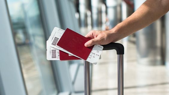 Mano con pasaporte y billetes en el aeropuerto, una imagen práctica para explicar si es obligatorio el seguro de viaje para ir a Europa.