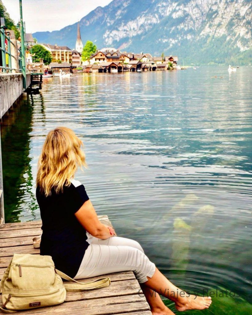 Una servidora contemplando un lago alpino en Europa, una imagen viajera para ilustrar si es obligatorio el seguro de viaje para ir a Europa.