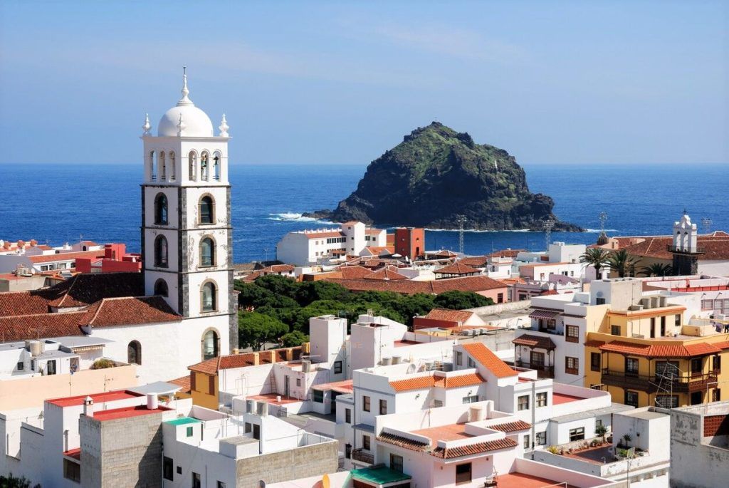 Vista de Garachico con su campanario blanco, casas tradicionales y el Roque de Garachico frente al mar, una imagen ideal para inspirar que ver en Tenerife en una semana.