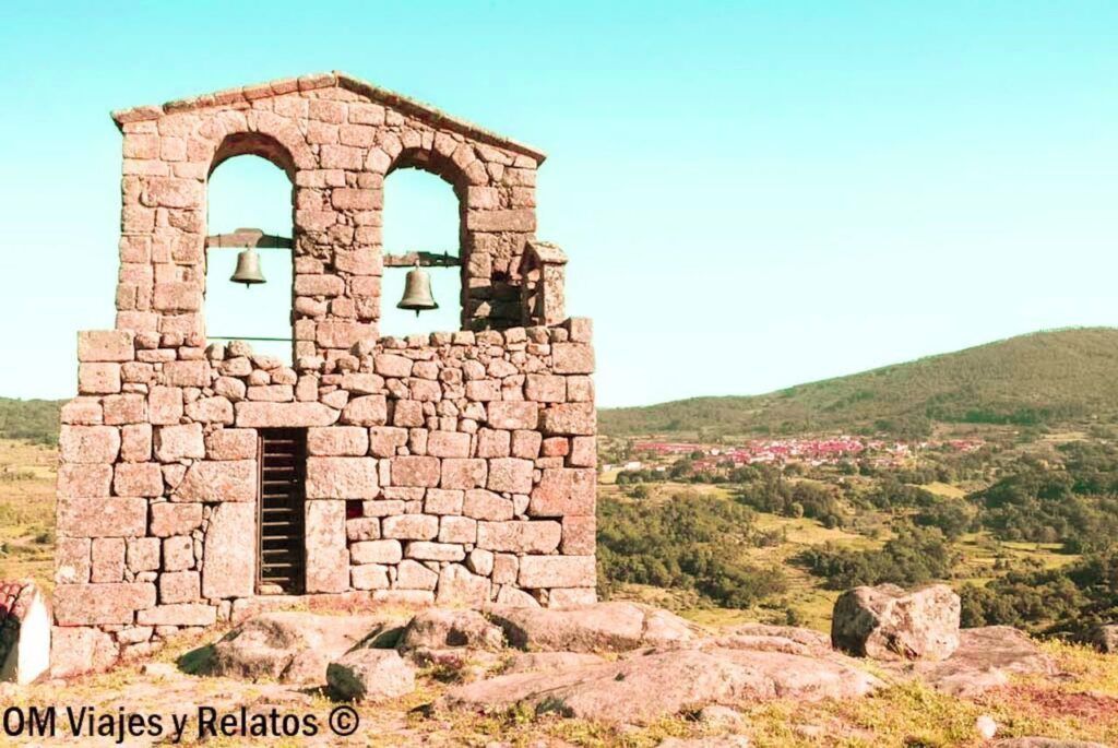 Campanario de piedra sobre una colina con vistas al valle y al pueblo, en uno de los pueblos más bonitos de Cáceres.
