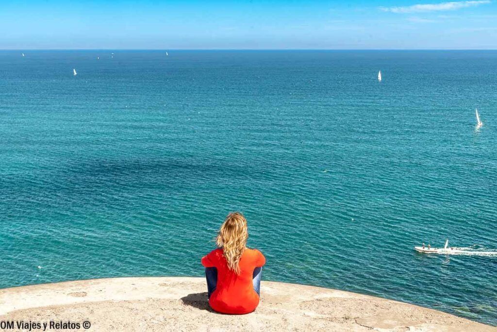 Una servidora contemplando el mar desde un mirador costero con veleros al fondo, pueblos costeros más bonitos de Asturias.