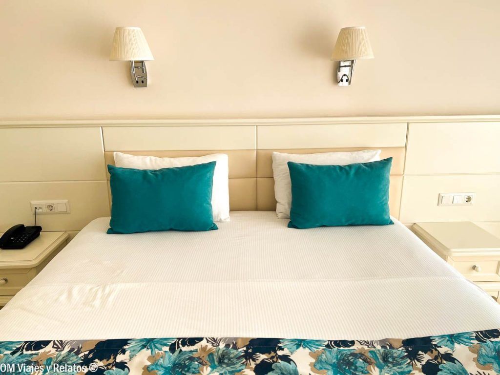 Habitación de hotel en Fethiye con cama doble y cojines turquesa, una estancia cómoda para descubrir que ver en Fethiye.