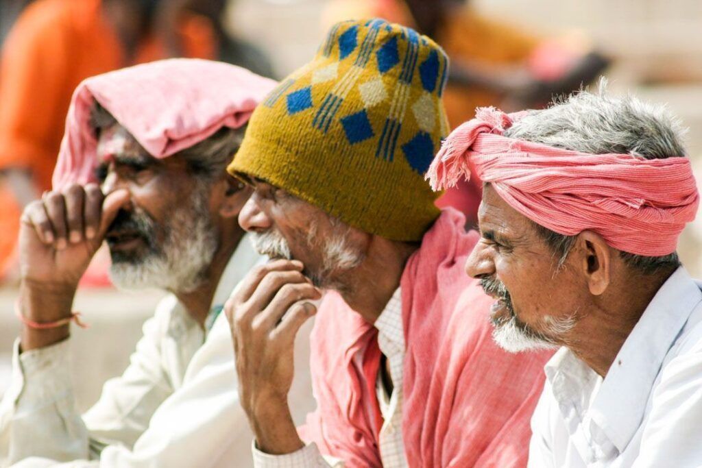 Hombres con turbantes y ropa tradicional descansando en India, una escena cotidiana para ilustrar consejos para viajar a la India.