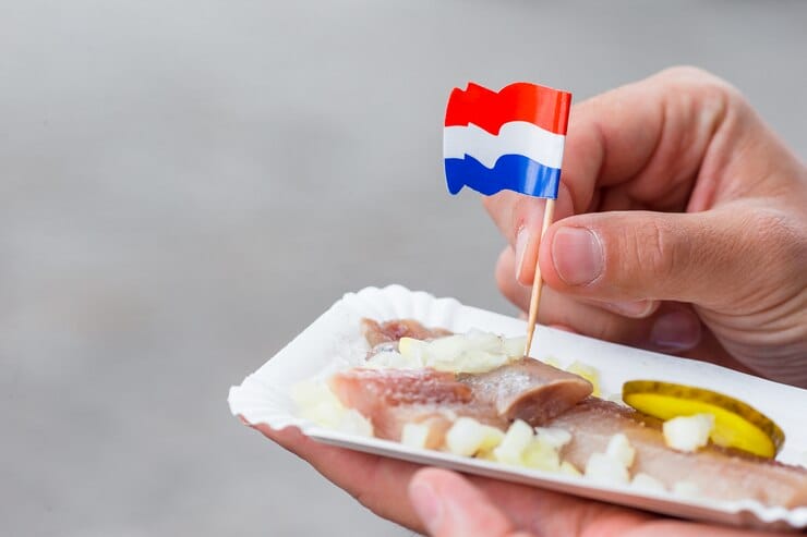 Arenque fresco con bandera holandesa, una comida típica para probar durante una ruta por Amsterdam en un día.