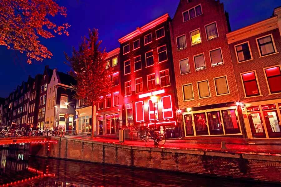 Barrio Rojo iluminado junto a un canal, una zona curiosa y famosa para conocer Ámsterdam en un día.