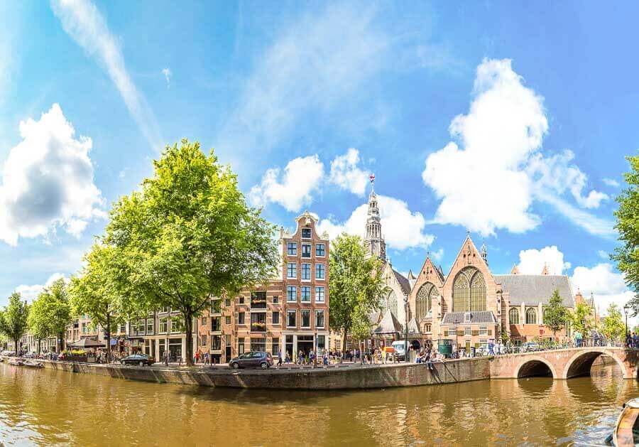 Canal de Ámsterdam con puente e iglesia histórica, una parada imprescindible sobre Amsterdam en un día.