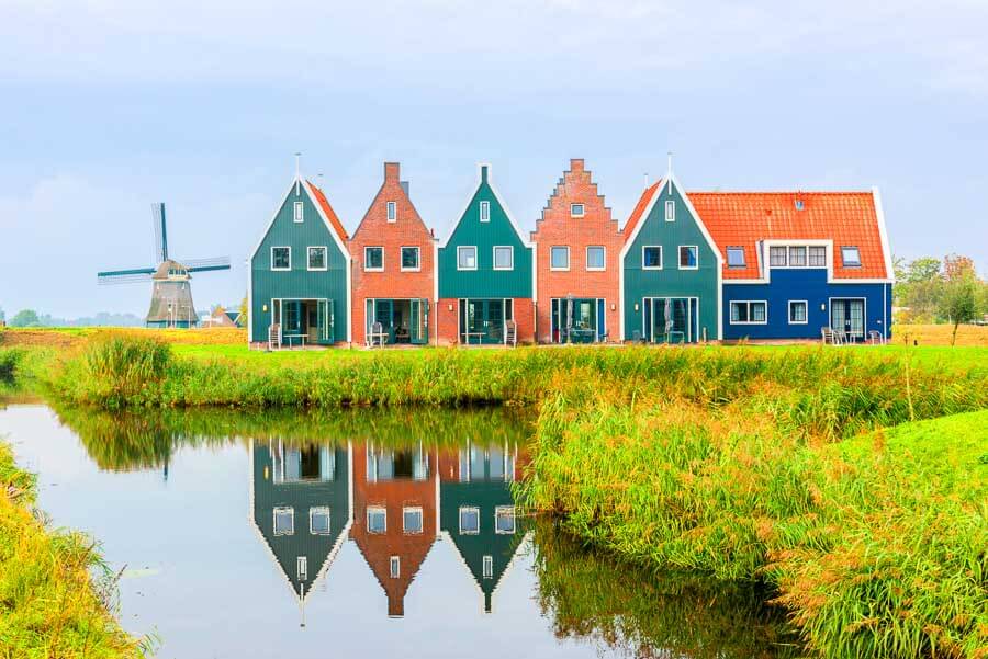 Excursión cerca de Ámsterdam con casas tradicionales y molino, una imagen ideal sobre Amsterdam en un día.