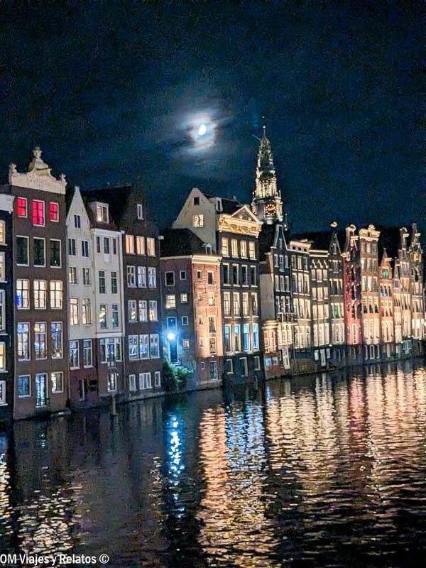 Canales de Ámsterdam iluminados de noche con casas reflejadas en el agua, una estampa mágica para terminar Amsterdam en un dia.
