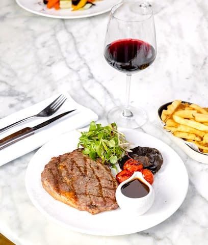 Plato de carne a la parrilla con vino tinto y guarnición, una experiencia culinaria deliciosa que ver en Edimburgo en 4 días.