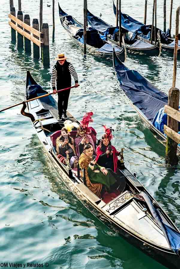 Góndola con pasajeros disfrazados por los canales de Venecia, una experiencia única que hacer en Venecia en Carnaval.