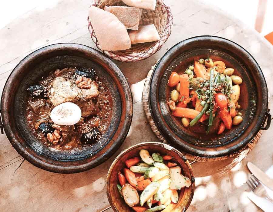 Viajar a Marrakech por libre: tajines marroquíes con verduras y carne, acompañados de ensalada y pan tradicional.