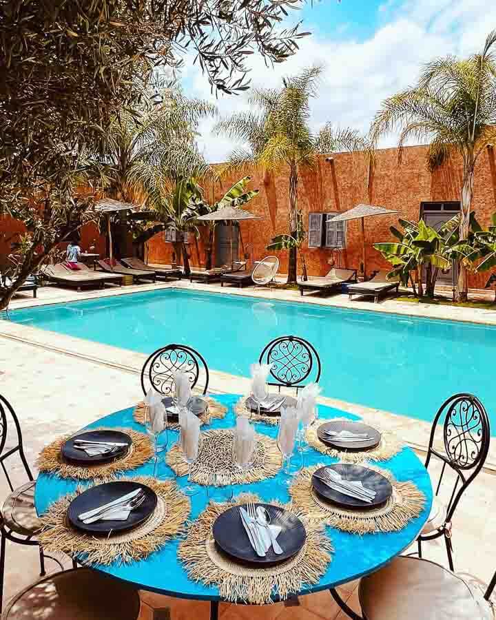 Piscina del Riad Le Coco Canel en Marrakech con tumbonas y comedor exterior, una opción relajante entre los mejores riads donde alojarse en Marrakech.