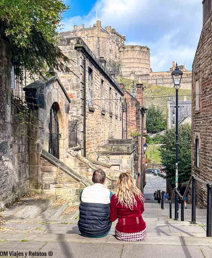 Yo y JC sentados en los escalones de The Vennel con vistas al Castillo de Edimburgo, un rincón romántico que ver en Edimburgo en 4 días.