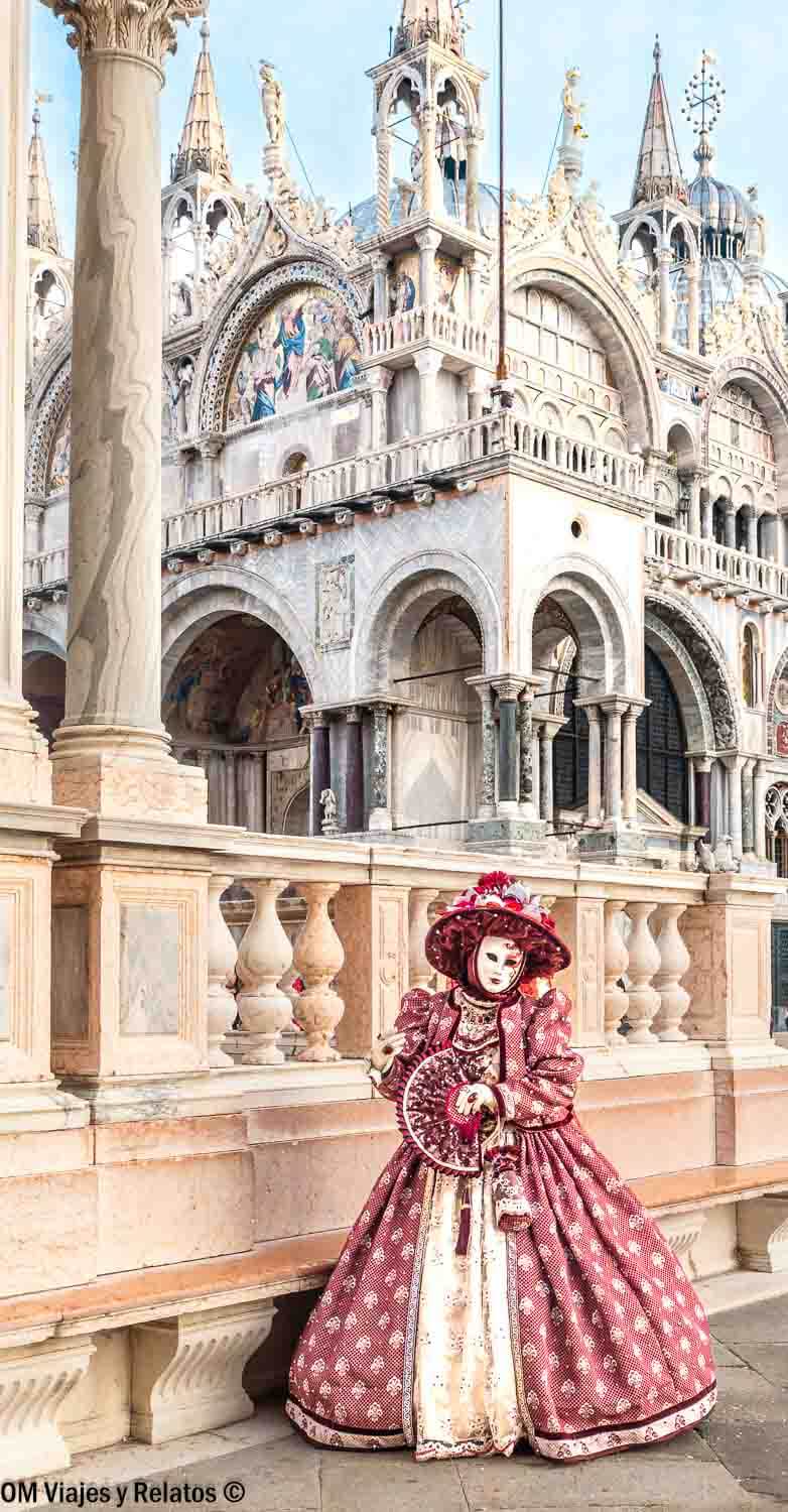Persona con traje y máscara del Carnaval posando frente a la Basílica de San Marcos, una foto icónica que hacer en Venecia en Carnaval.