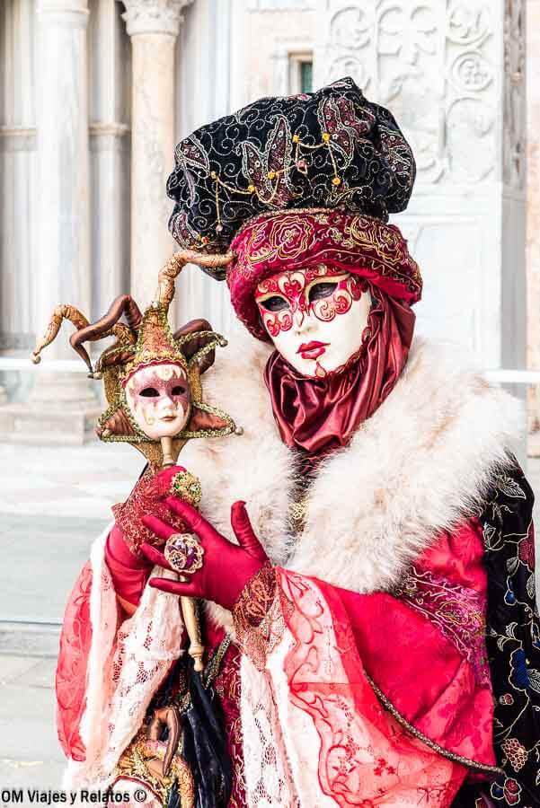 Máscara veneciana roja con tocado y arlequín en la Plaza de San Marcos, una foto imprescindible que hacer en Venecia en Carnaval.