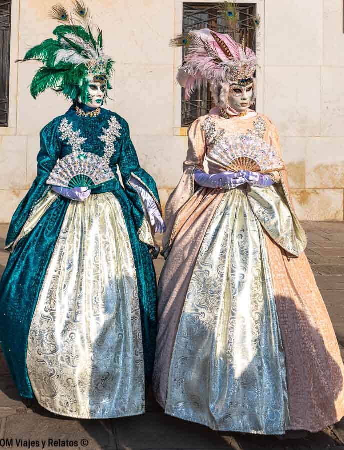 Dos personas con máscaras y trajes elegantes con plumas en Venecia, una foto imprescindible que hacer en Venecia en Carnaval.