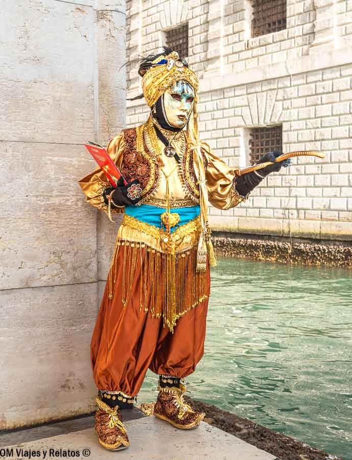 Personaje con máscara y traje dorado estilo oriental junto al canal, una escena original que hacer en Venecia en Carnaval.