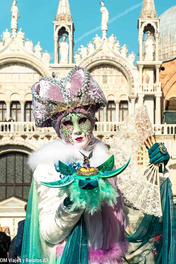 Máscara veneciana con abanico y traje verde en la Plaza de San Marcos, una foto espectacular que hacer en Venecia en Carnaval.