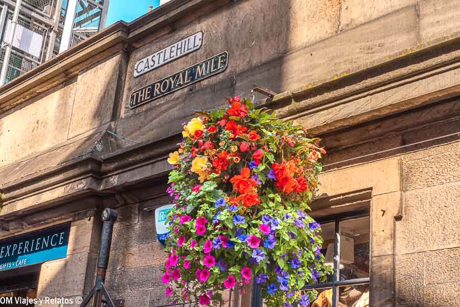 Cartel de The Royal Mile con flores colgantes en Castlehill, uno de los tramos más representativos que ver en Edimburgo en 4 días.