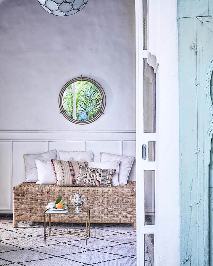 Rincón elegante de un riad en Marrakech con sofá de fibras naturales y decoración cuidada, ideal entre los mejores riads donde alojarse en Marrakech.