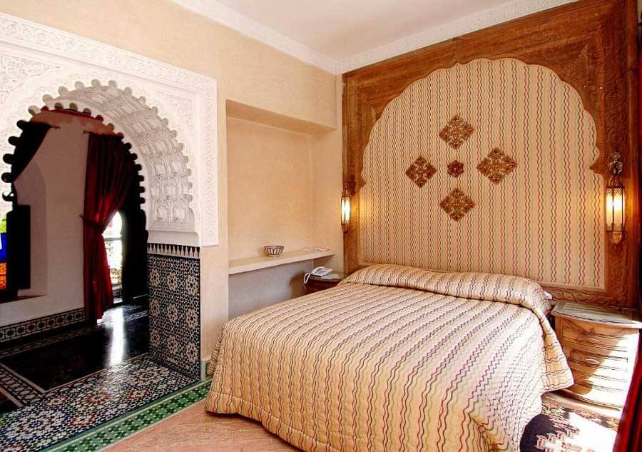 Habitación del riad Palais Sebban en Marrakech con arco árabe y cabecero decorado, una opción elegante entre los mejores riads donde alojarse en Marrakech.