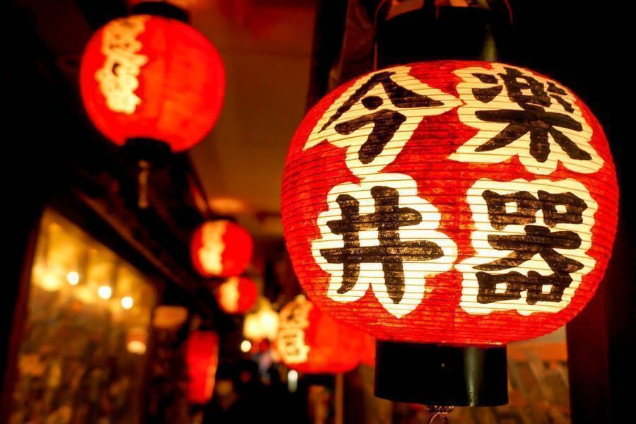 Farolillos rojos japoneses iluminando una calle nocturna, consejos para viajar a Japón por libre: aprender frases básicas y llevar datos o eSIM para orientarte.