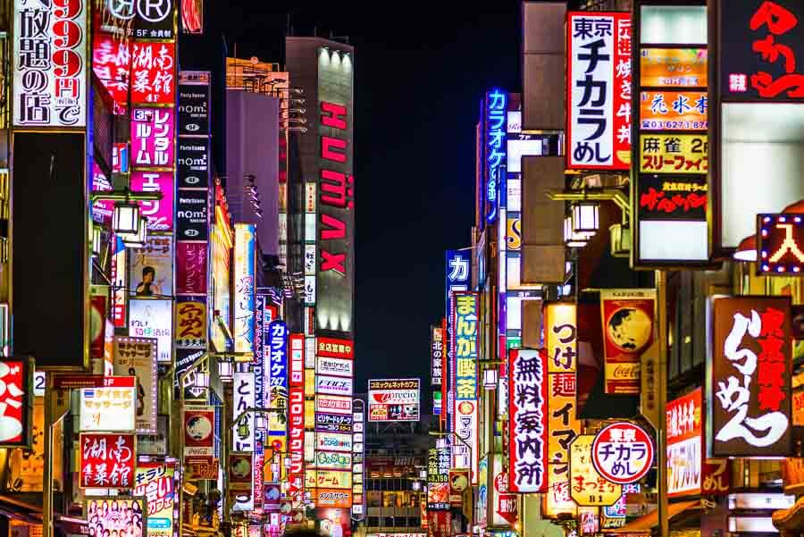 Calles de Tokio con neones y carteles japoneses de noche, consejos para viajar a Japón por libre: moverte en metro y llevar mapas offline para no perderte.