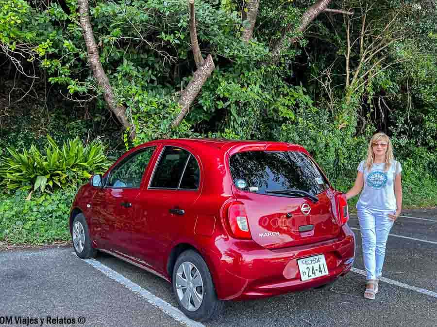 Coche de alquiler en Japón con una servidora junto al vehículo, consejos para viajar a Japón por libre: alquilar coche solo en zonas rurales y llevar permiso internacional.