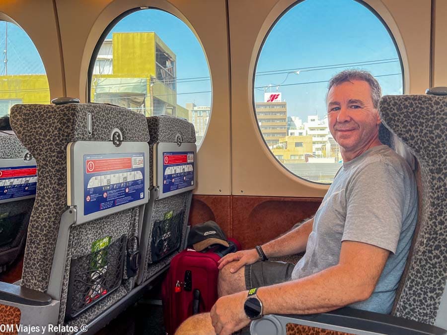 JC viajando en tren en Japón con equipaje junto a la ventana, consejos para viajar a Japón por libre: reservar asientos y llevar maleta compacta.