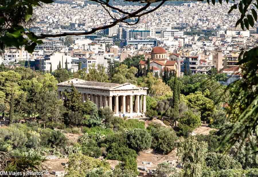 Vista panorámica de Atenas con un templo clásico rodeado de vegetación, un plan ideal en que ver en Atenas en 1 día.