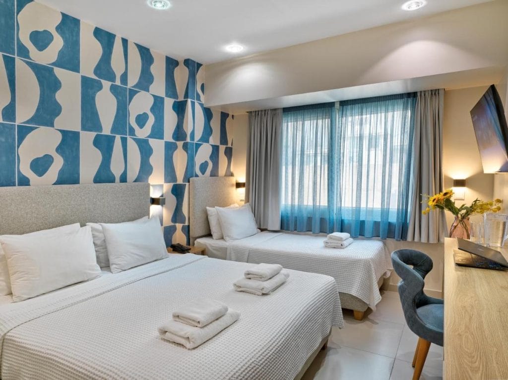 Habitación familiar de hotel en Atenas con dos camas y decoración moderna, una opción práctica si estás pensando donde alojarse en Atenas.