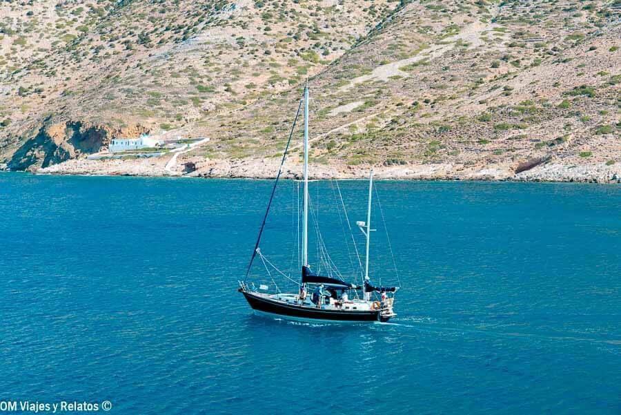 Velero navegando frente a la costa de Milos con aguas azules, plan en barco para descubrir las mejores playas de Milos.